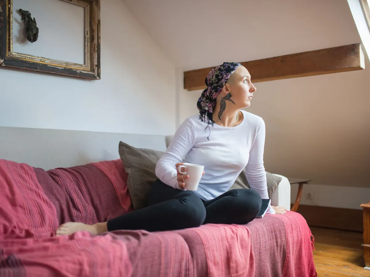 Vrouw zit ontspannen op de bank met een kop thee en kijkt uit het dakraam